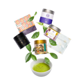 A curated flat-lay of matcha tea products on a white background, including several metal tins with colorful labels, a patterned box, a white sachet, and a white bowl filled with bright green matcha powder, accented by green tea leaves.